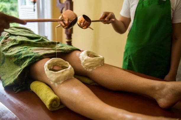 Warm medicated oil poured into dough rings built over both knees.